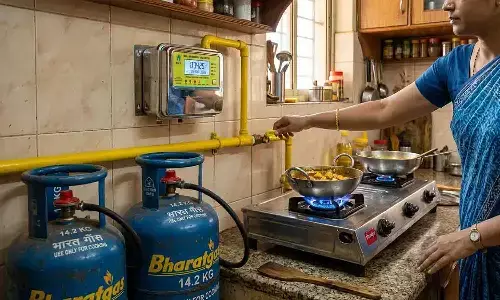 एक भारतीय रसोई में महिला कुकिंग गैस का वॉल्व चालू कर रही है।